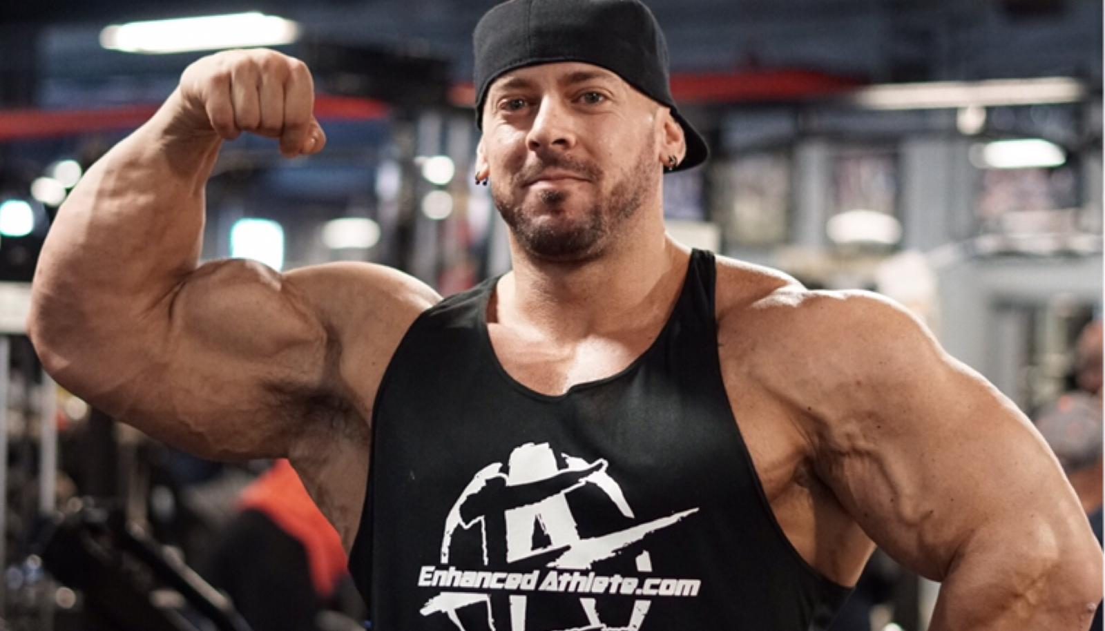 Coach Trevor hitting a front double bicep in an Enhanced Athlete tank top
